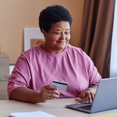 woman sitting in front of laptop holding a credit card